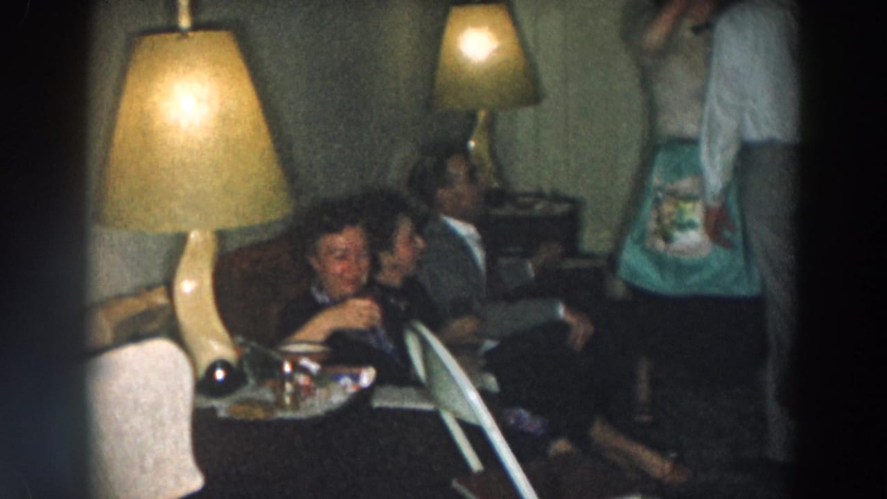 Adults seated on a couch in a dim living room with glowing table lamps.