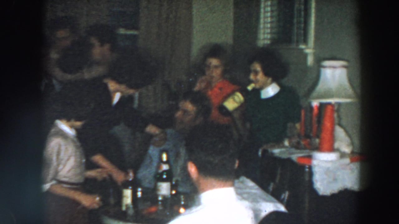 Adults socialize around a table with bottles during a 1957 Wheeling, Ohio home party, with a lamp and doorway visible.