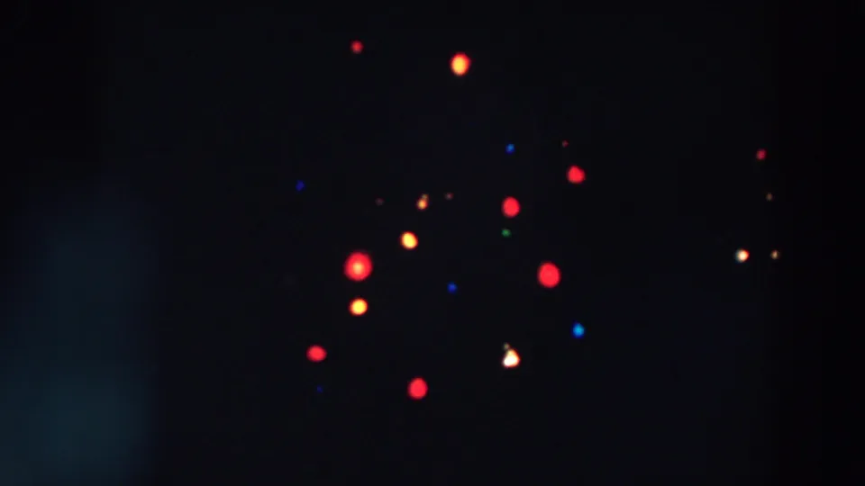1957 8mm frame of red, yellow, blue, and green lights in soft focus, likely part of a night decoration in Wheeling, Ohio.