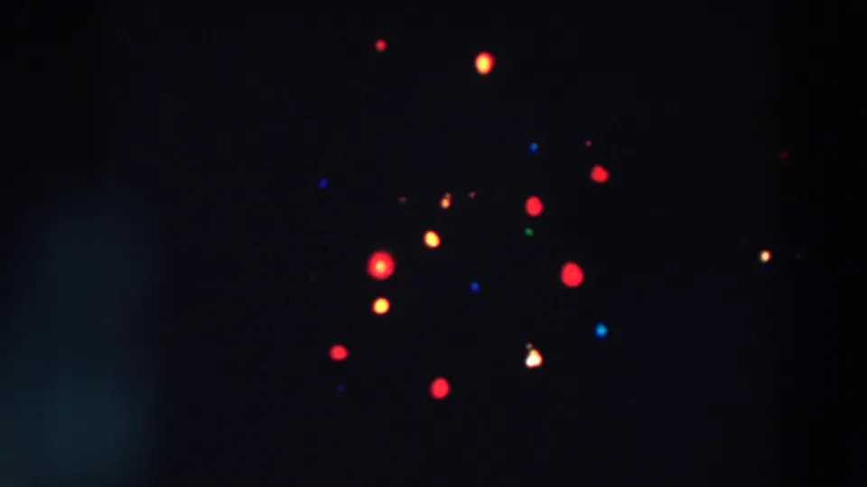 Wheeling, Ohio 1957 home-movie frame with distant red and yellow lights and smaller blue and green points in deep darkness.