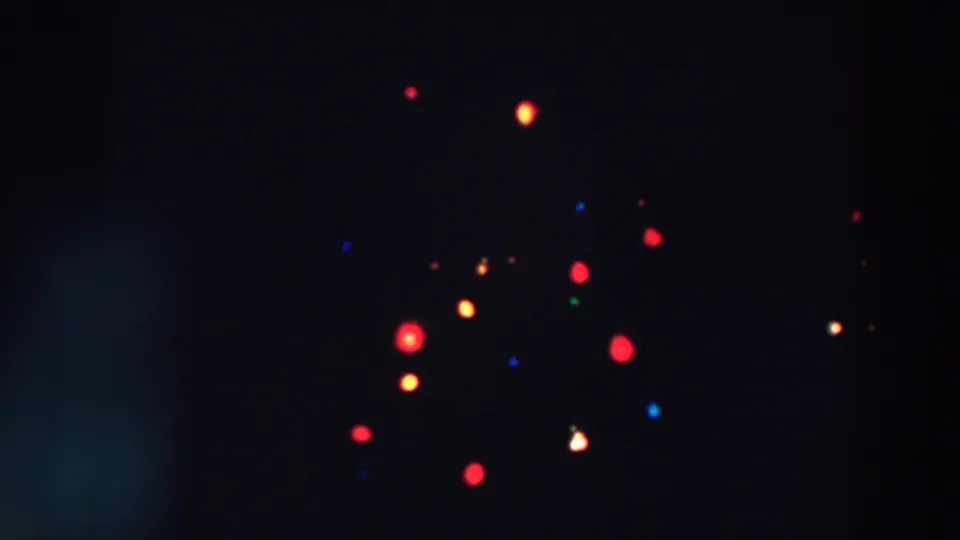 1957 Wheeling, Ohio 8mm frame showing dim, soft-focus Christmas tree lights with strong grain and a dark interior background.
