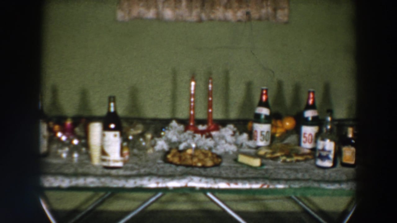 Serving table with bottles, cups, red candles, white garland, and plates of food.
