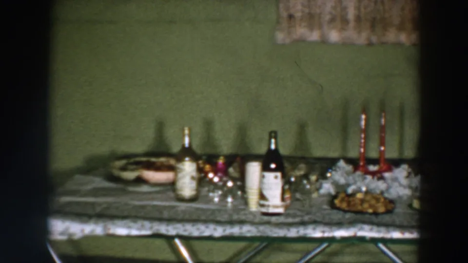 1957 Wheeling, Ohio frame showing the refreshment table with beverage bottles, paper cups, red taper candles, garland, and food.