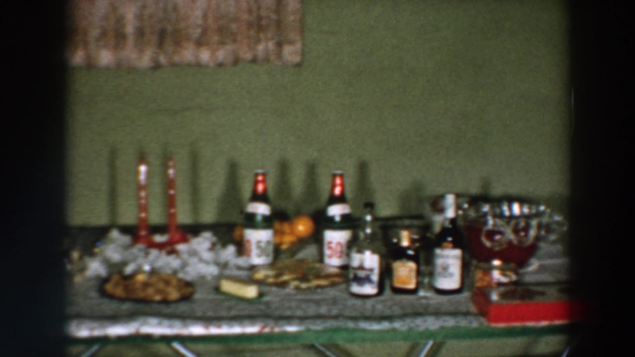 1957 Wheeling, Ohio home-movie frame showing a celebration table with bottled drinks, candles, snacks, and a punch bowl.