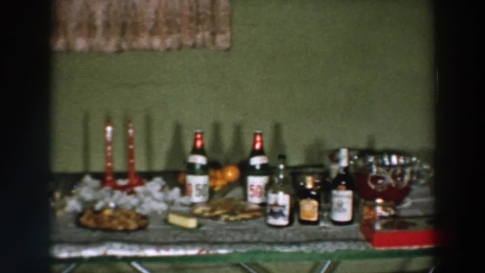 1957 Wheeling, Ohio home-movie frame showing a celebration table with bottled drinks, candles, snacks, and a punch bowl.