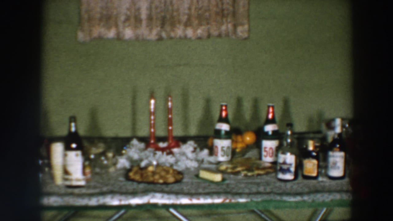 1957 Wheeling, Ohio frame of a decorated party table with visible bottle labels, candles, food, and fruit.