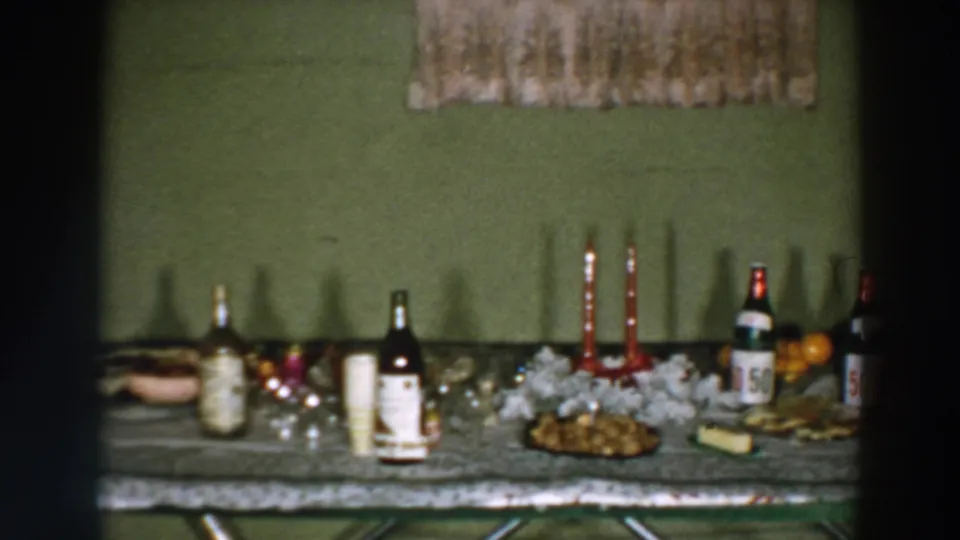 1957 Wheeling, Ohio home interior frame with a long table holding bottled drinks, candles, snacks, and serving dishes.