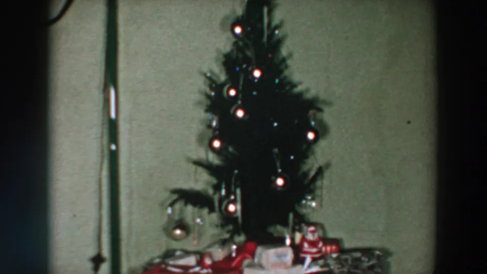 Final frame shows the small decorated tree glowing above wrapped gifts in a 1957 Wheeling, Ohio home movie.