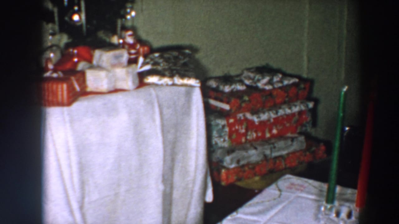 1957 Wheeling, Ohio Christmas interior with a white-covered table, wrapped presents, candles, and stacked gift boxes.