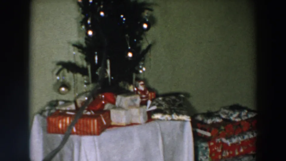 1957 Wheeling, Ohio holiday home interior with the Christmas tree partly above a table of wrapped presents and boxes.