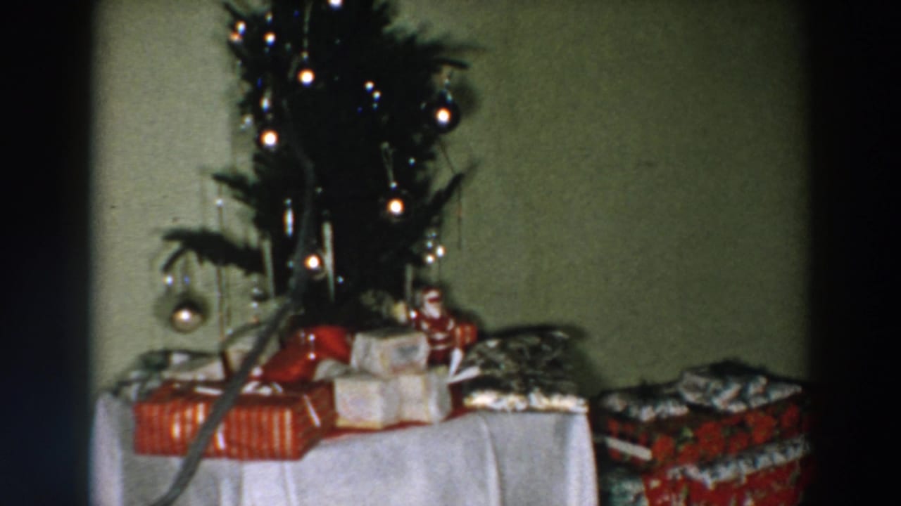 Small decorated Christmas tree beside wrapped presents on a table.