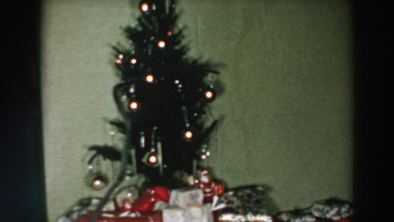 1957 Wheeling, Ohio home-movie view of a decorated Christmas tree with gifts and ornaments in a modest interior.