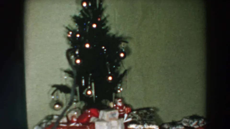 1957 Wheeling, Ohio home-movie view of a decorated Christmas tree with gifts and ornaments in a modest interior.