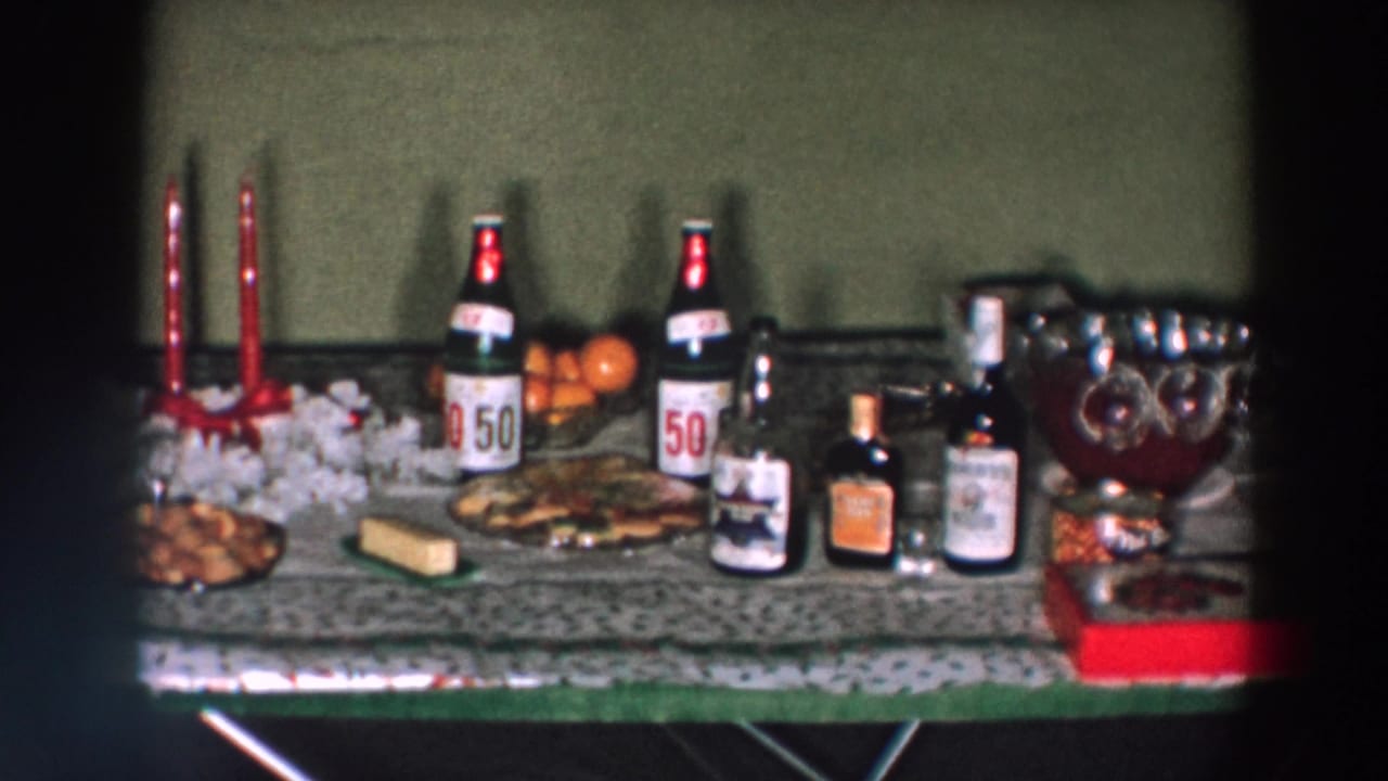Holiday drinks and snacks table in a 1957 Wheeling, Ohio home movie, with labeled bottles, candles, oranges, and a punch bowl.