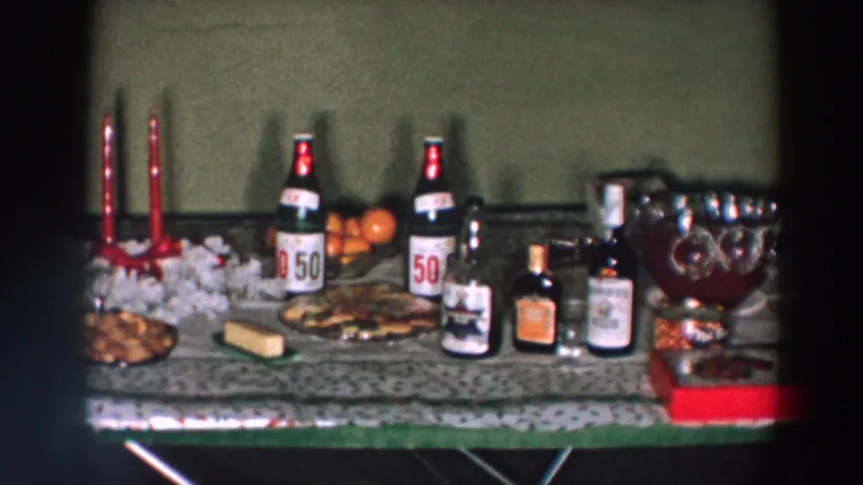 Holiday drinks and snacks table in a 1957 Wheeling, Ohio home movie, with labeled bottles, candles, oranges, and a punch bowl.