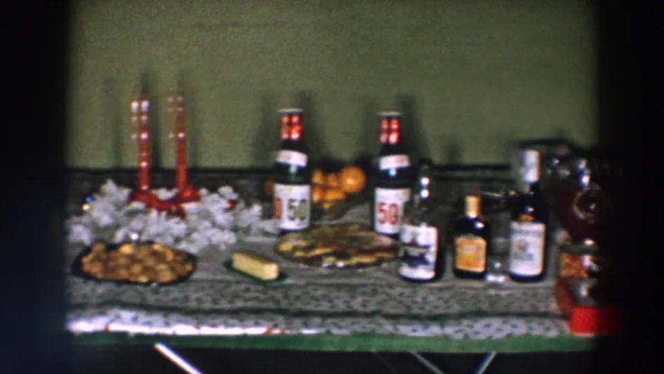 1957 Wheeling, Ohio holiday table with red candles, beer bottles, liquor bottles, snacks, oranges, and punch bowl.