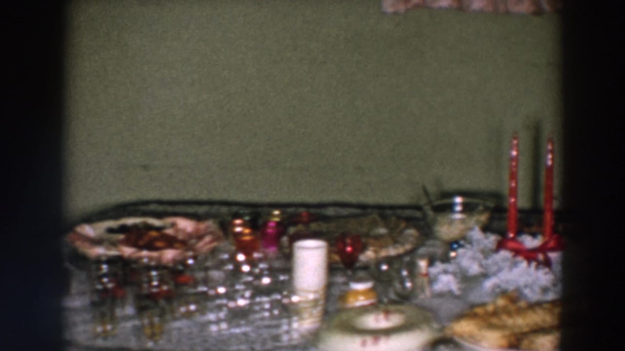 Tabletop spread with glassware, serving dishes, red candles, and a bottle near the right edge.