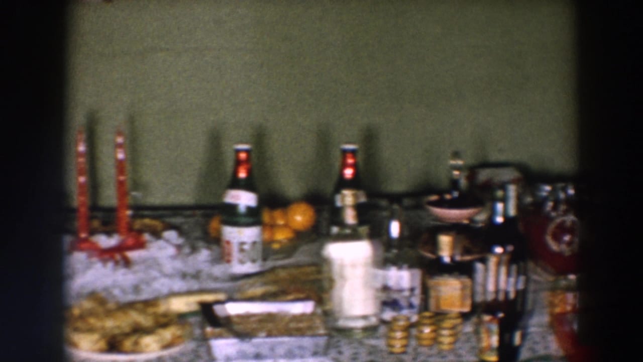 Color 8mm frame from the Wheeling party table with red candles, beverage bottles, oranges, punch bowl, and dessert trays.