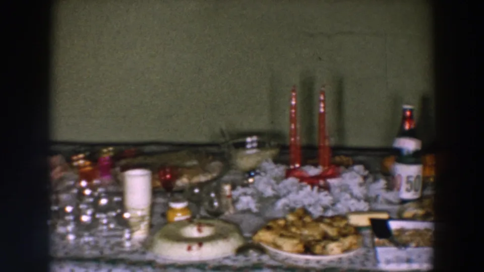 Wheeling, Ohio party-table frame showing a punch bowl, glassware, desserts, red candles, bottled drinks, and white decorative material.