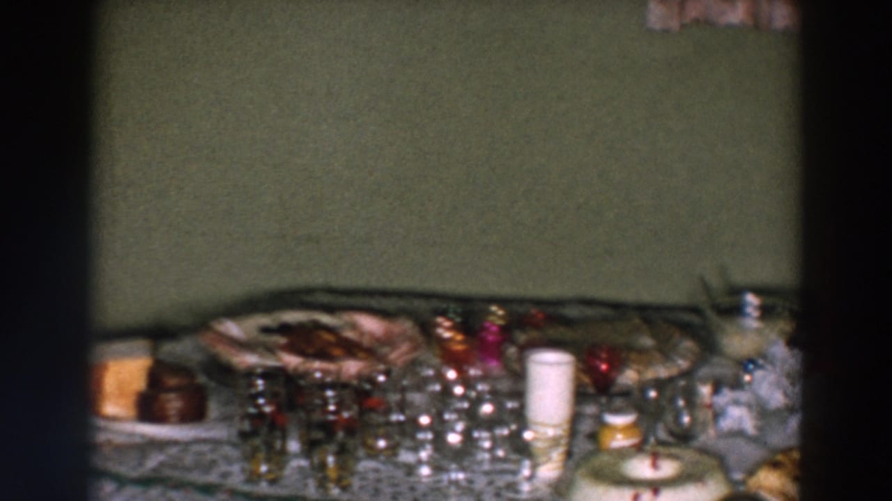 Holiday table spread with glasses, candles, food, and a wreath-shaped dessert near the front.