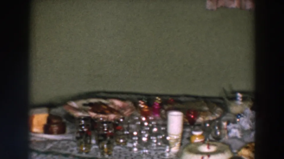 1957 Wheeling, Ohio home-movie still of a decorated holiday table with glassware, candles, food trays, and a wreath-shaped dessert.