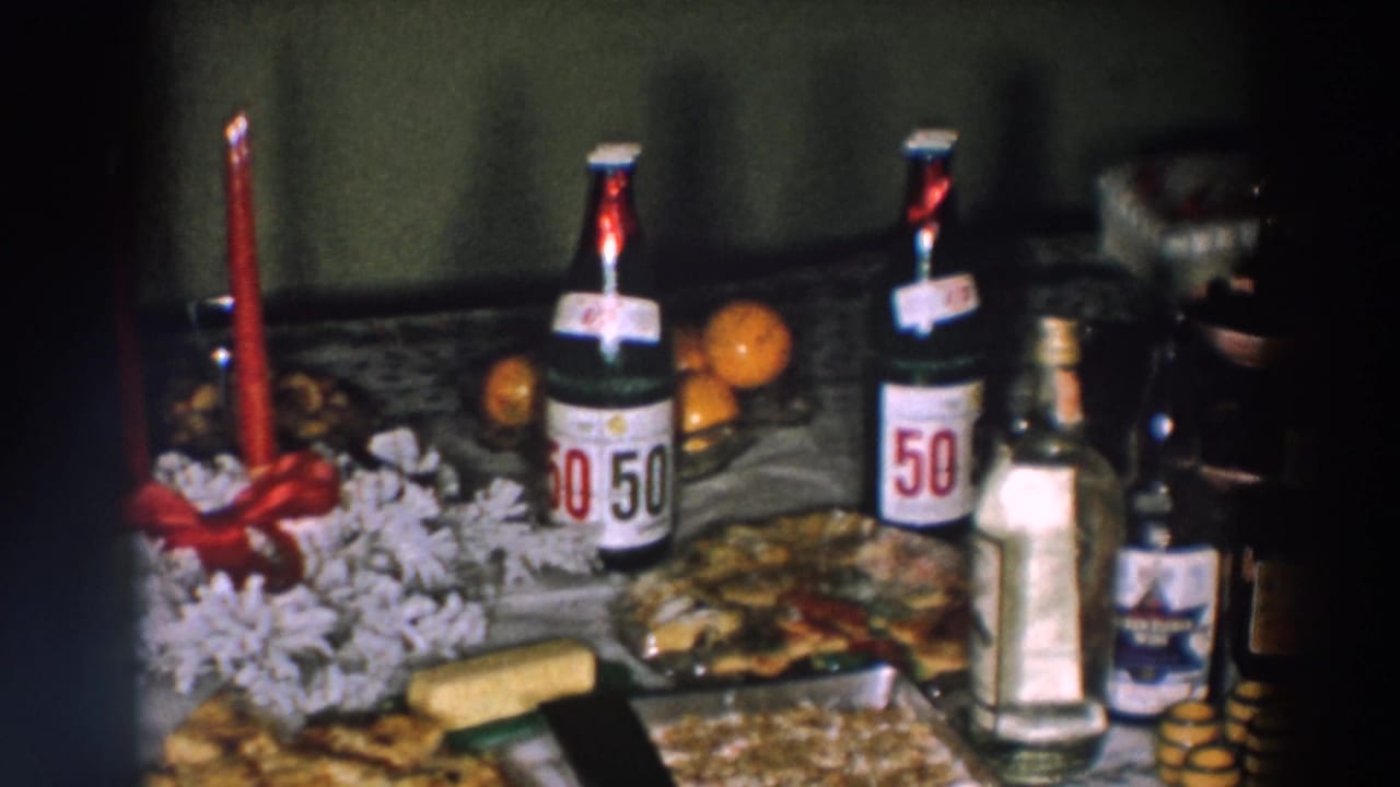 1957 Wheeling, Ohio table detail with two 50/50 soda bottles, a red candle, oranges, prepared food, and additional beverage bottles.