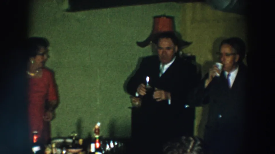 Adults at a 1957 Wheeling, Ohio indoor gathering hold drinks as they stand beside bottles and glassware.