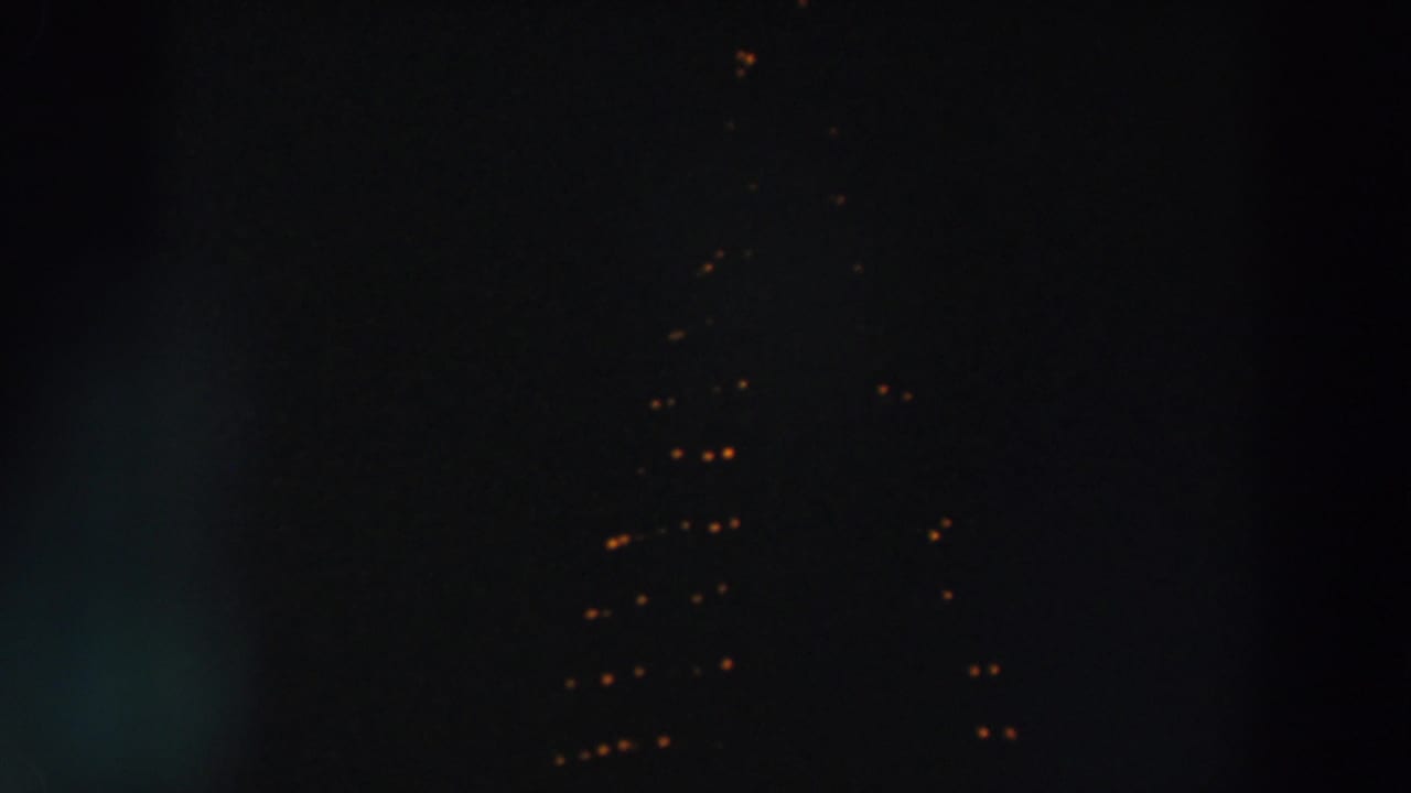 1957 Wheeling, Ohio 8mm frame showing distant warm string lights forming a triangular pattern against a dark night sky.