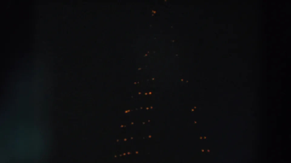 1957 Wheeling, Ohio 8mm frame showing distant warm string lights forming a triangular pattern against a dark night sky.