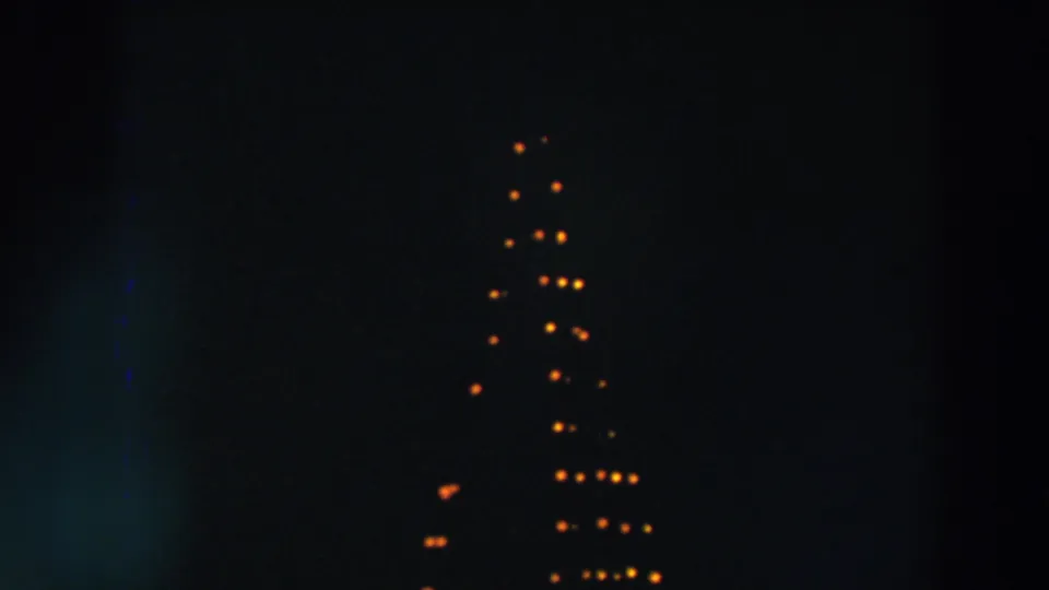 1957 Wheeling, Ohio home-movie frame with warm bulbs arranged like a tall triangular holiday display in darkness.