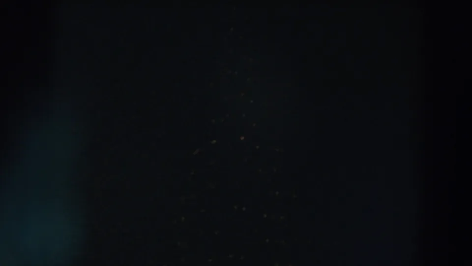 Low-light 1957 8mm view of a mostly dark urban building area in Wheeling, Ohio, with only faint lights visible.