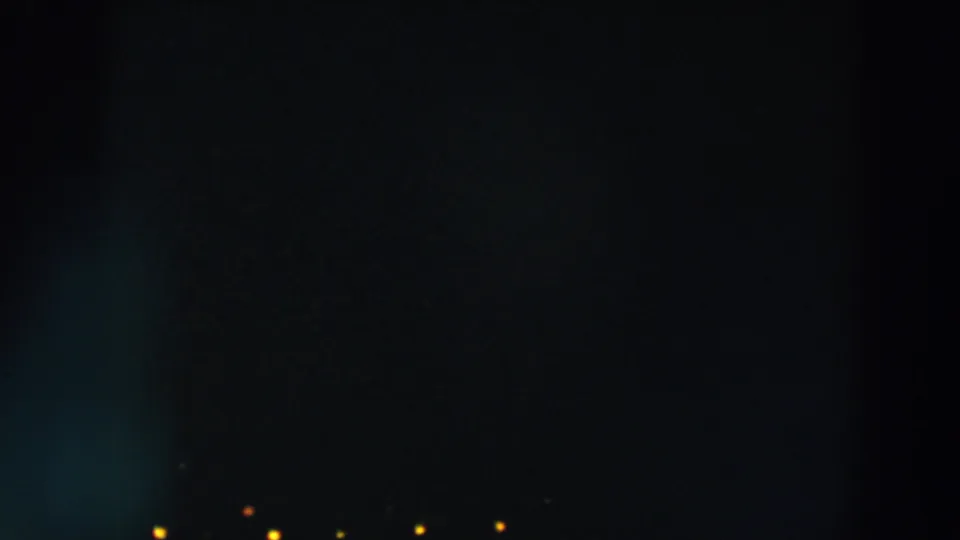 Final 1957 8mm night view in Wheeling, Ohio, showing scattered small lights against a mostly dark urban exterior.