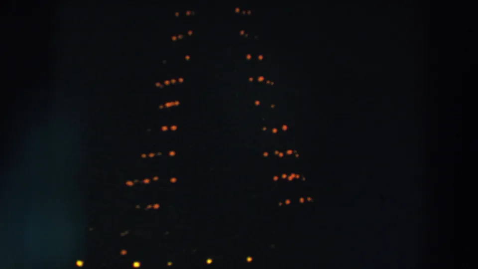 1957 Wheeling, Ohio 8mm frame showing warm holiday bulbs in a tree-like shape against a dark night sky.