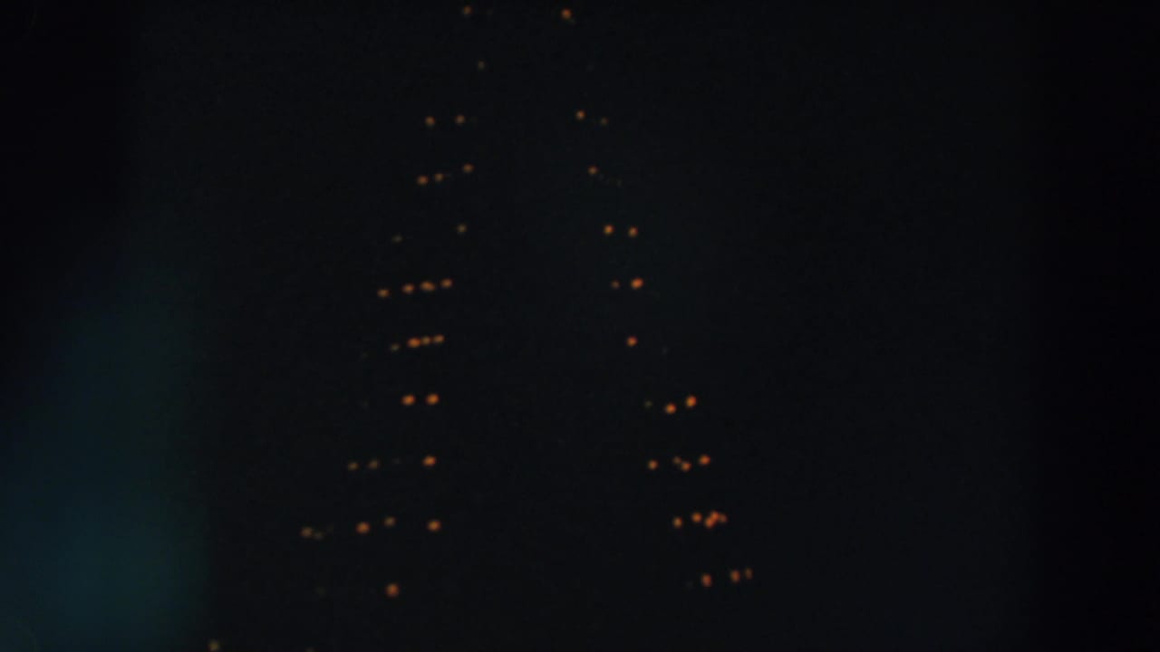 1957 Wheeling, Ohio nighttime home-movie frame with faint warm holiday lights and soft vertical flare.