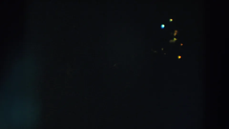 Dim 8mm frame showing clustered distant lights at right, with the rest of the Wheeling night scene mostly black.