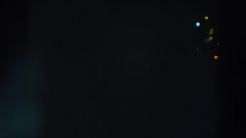 1957 8mm home-movie frame from Wheeling, Ohio, showing small red, yellow, and blue lights against a dark night field.