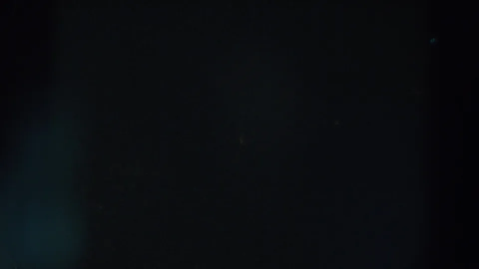 Soft colored points cluster near the upper left in this dark 1957 Wheeling, Ohio 8mm holiday-light frame.