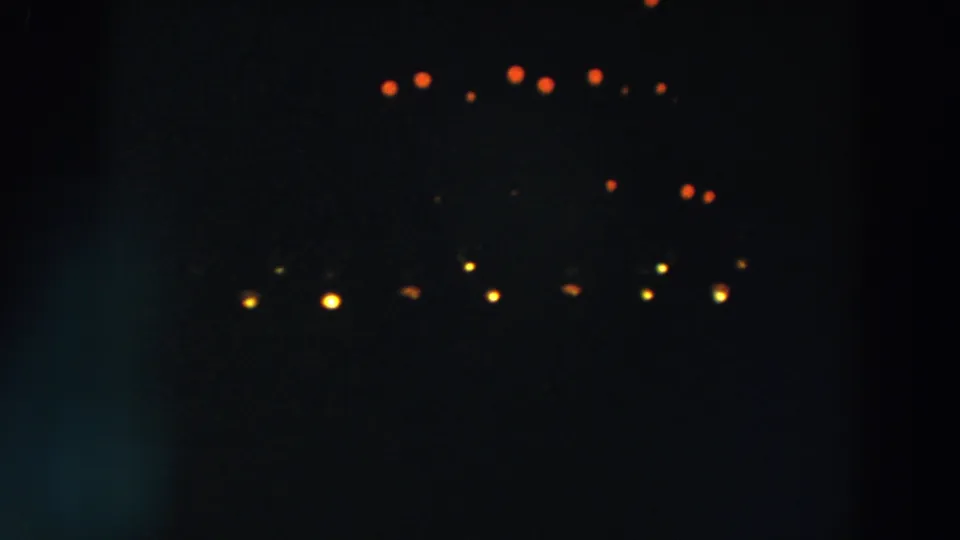 Red and yellow lights form loose rows across the darkness in this 1957 8mm Wheeling, Ohio holiday-light view.
