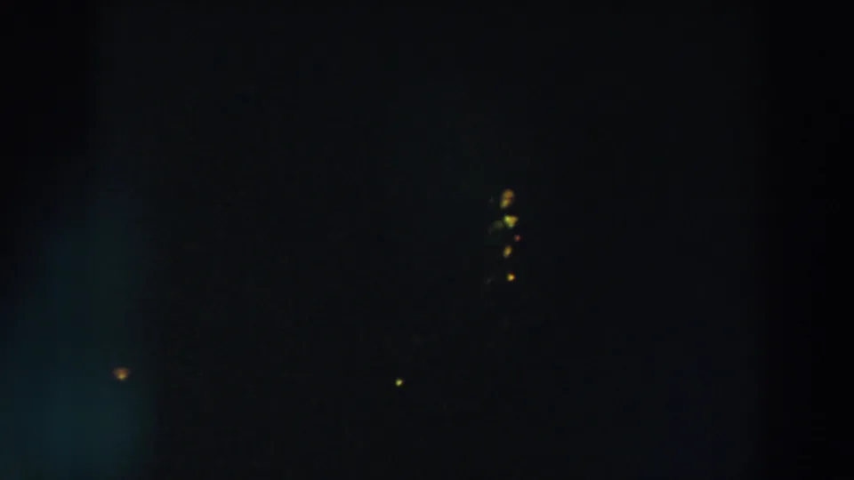 1957 Wheeling, Ohio 8mm frame showing distant yellow-orange lights against a nearly black evening sky.