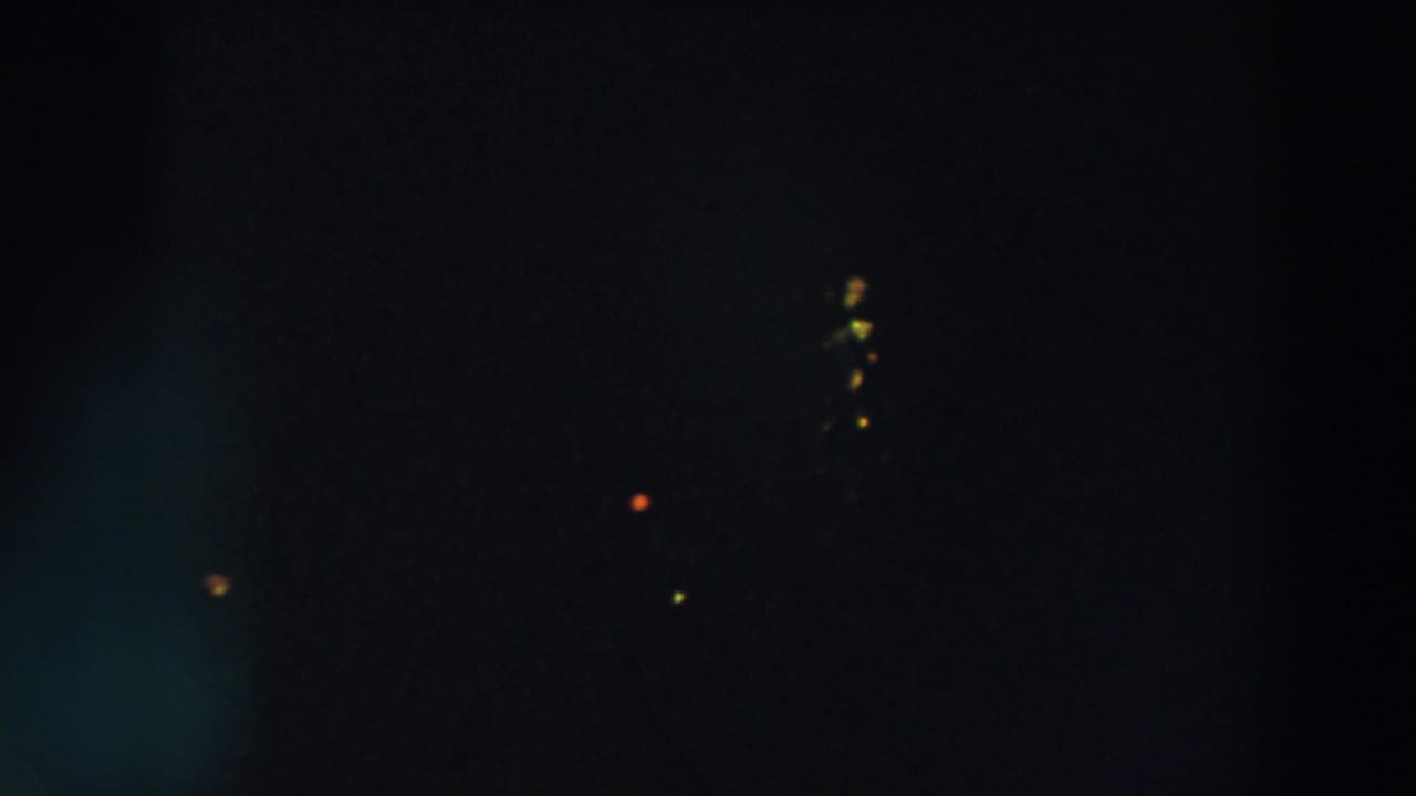 Dark 8mm night view from Wheeling, Ohio, with scattered yellow and orange lights and faint lens glow.