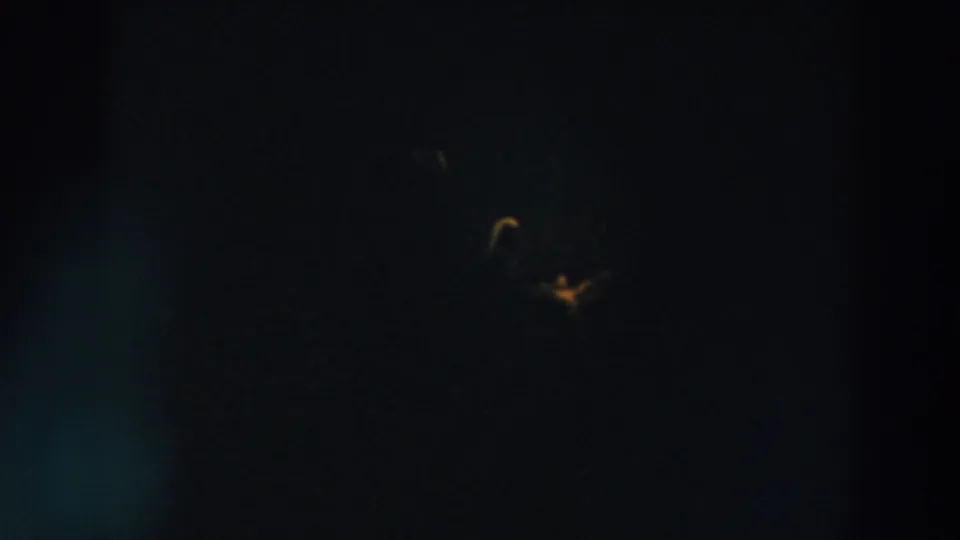 Wheeling, Ohio nighttime 8mm frame with a distant upper light cluster and dim orange glow near the lower frame.