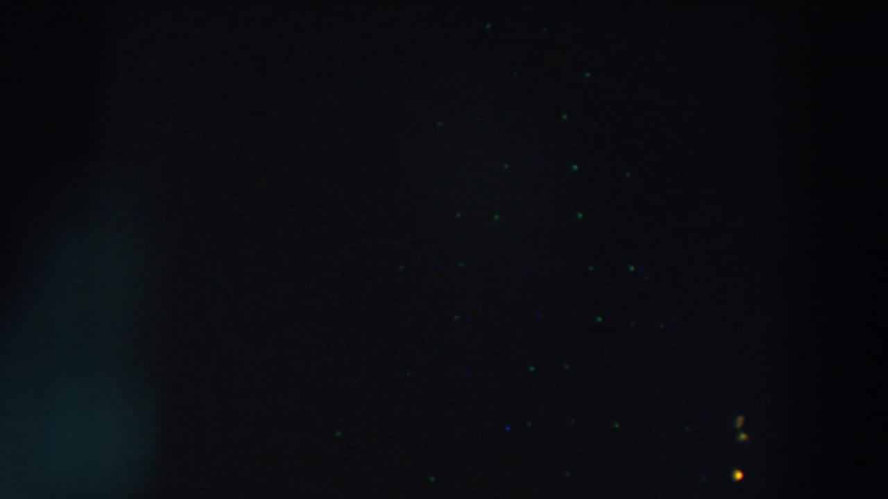 Dark frame with scattered light points and partial yellow letters at the right edge.