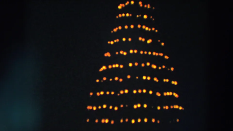 1957 Wheeling, Ohio night frame with yellow Christmas tree lights and partial illuminated MERRY sign above.