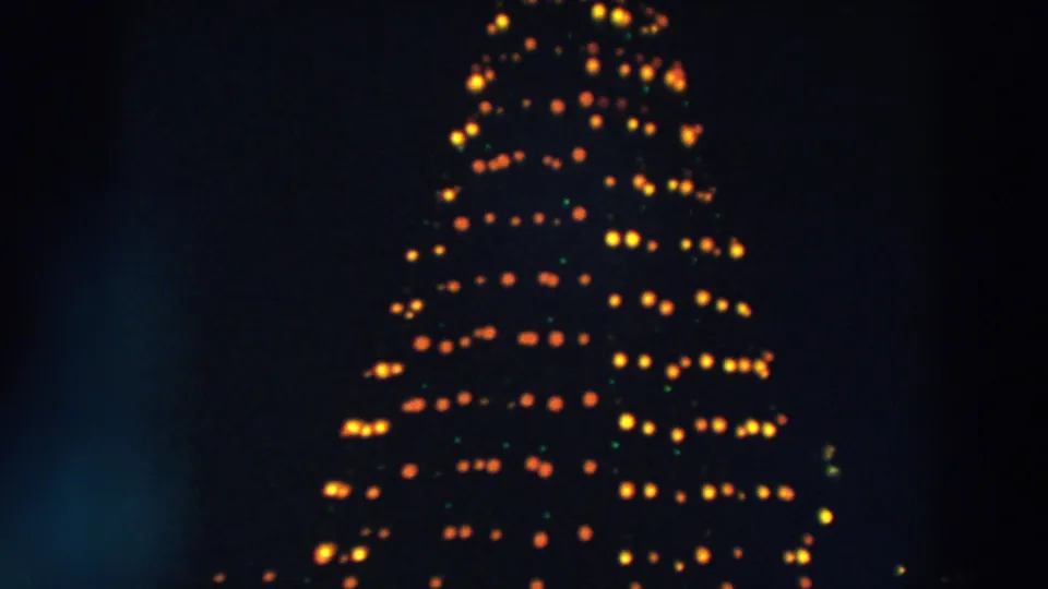 1957 Wheeling, Ohio home-movie frame showing a tall Christmas tree-shaped light display glowing in warm rows at night.