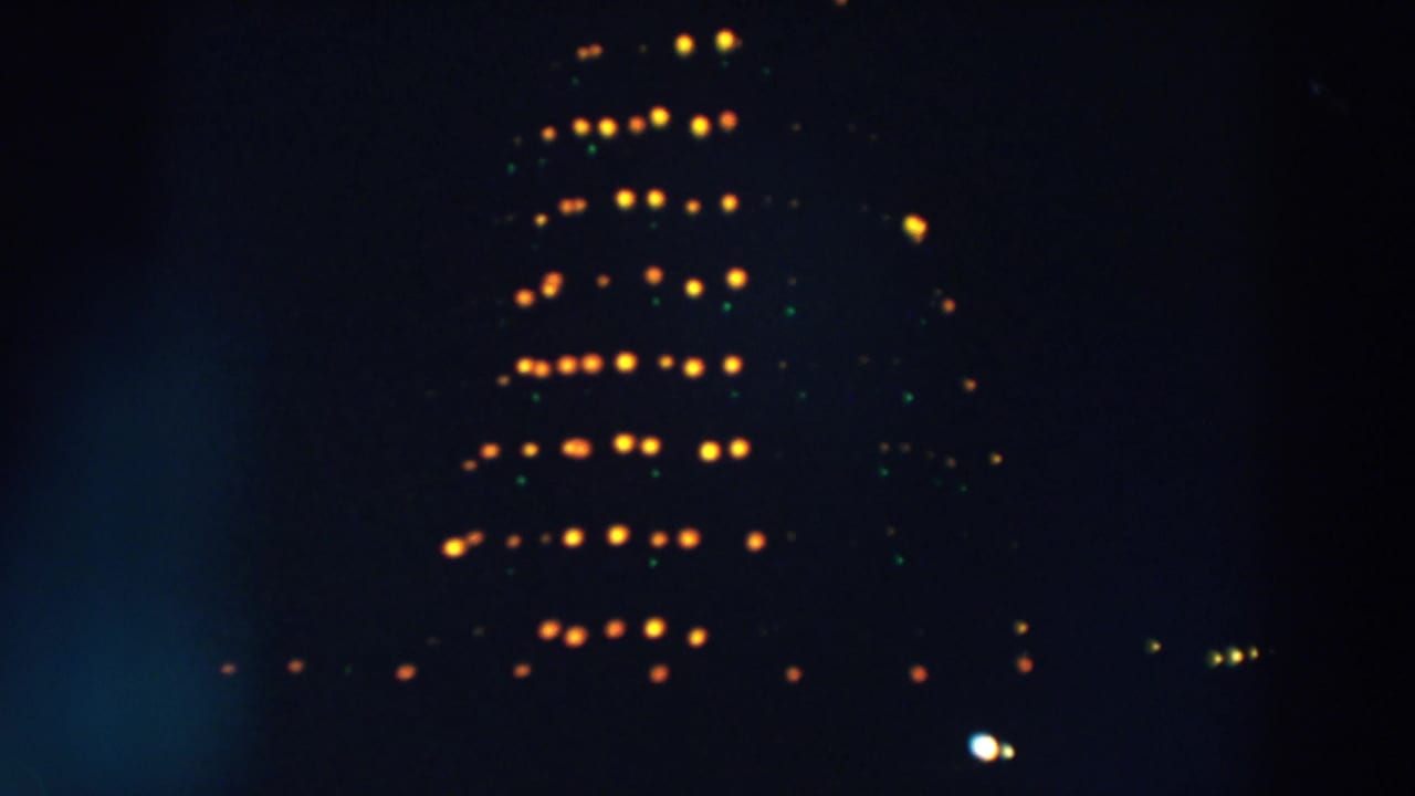 1957 Wheeling, Ohio frame with a distant tiered Christmas light form, partly softened by darkness and film blur.