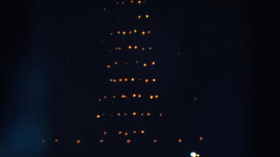 1957 Wheeling, Ohio frame with scattered orange and yellow bulbs from a Christmas light display fading into the dark frame.