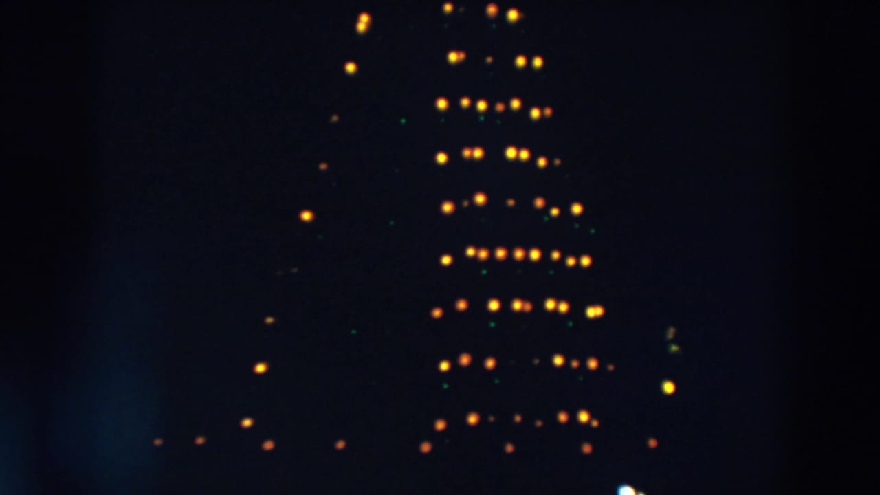 Tall pattern of glowing yellow and green lights against a dark background.