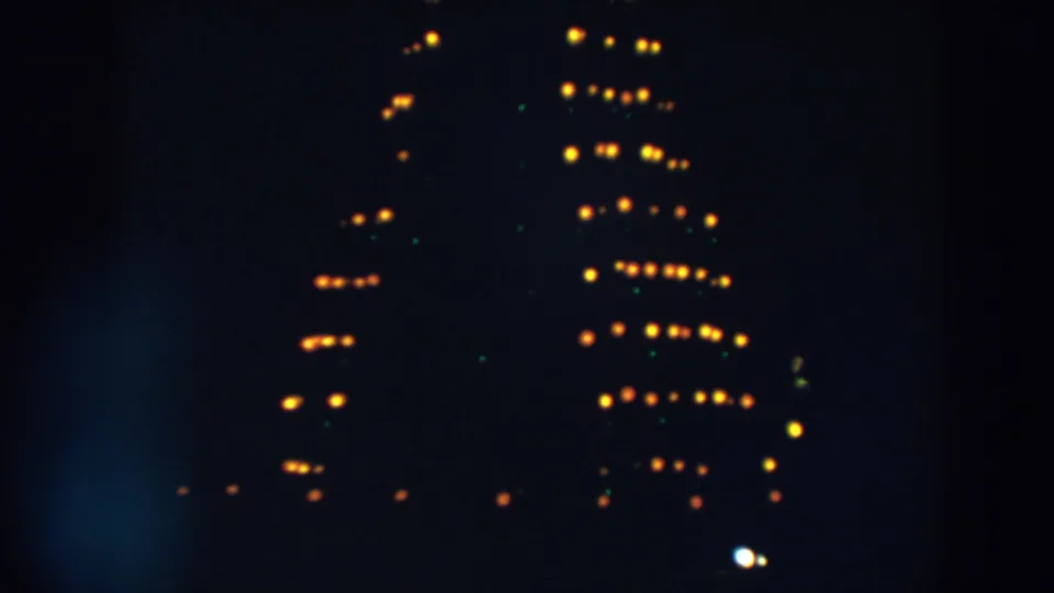 1957 Wheeling, Ohio 8mm frame showing a lower portion of blurred yellow lights and faint green points at night.