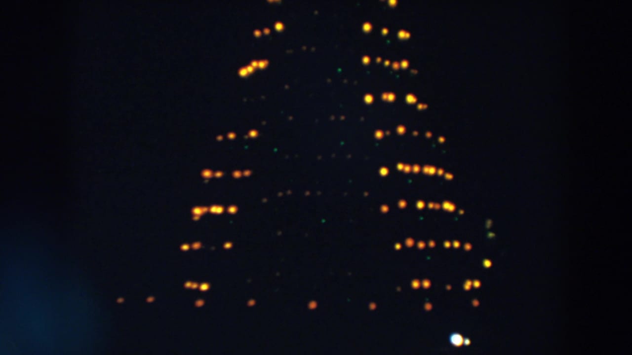 Triangular rows of yellow lights glow against a dark night sky.