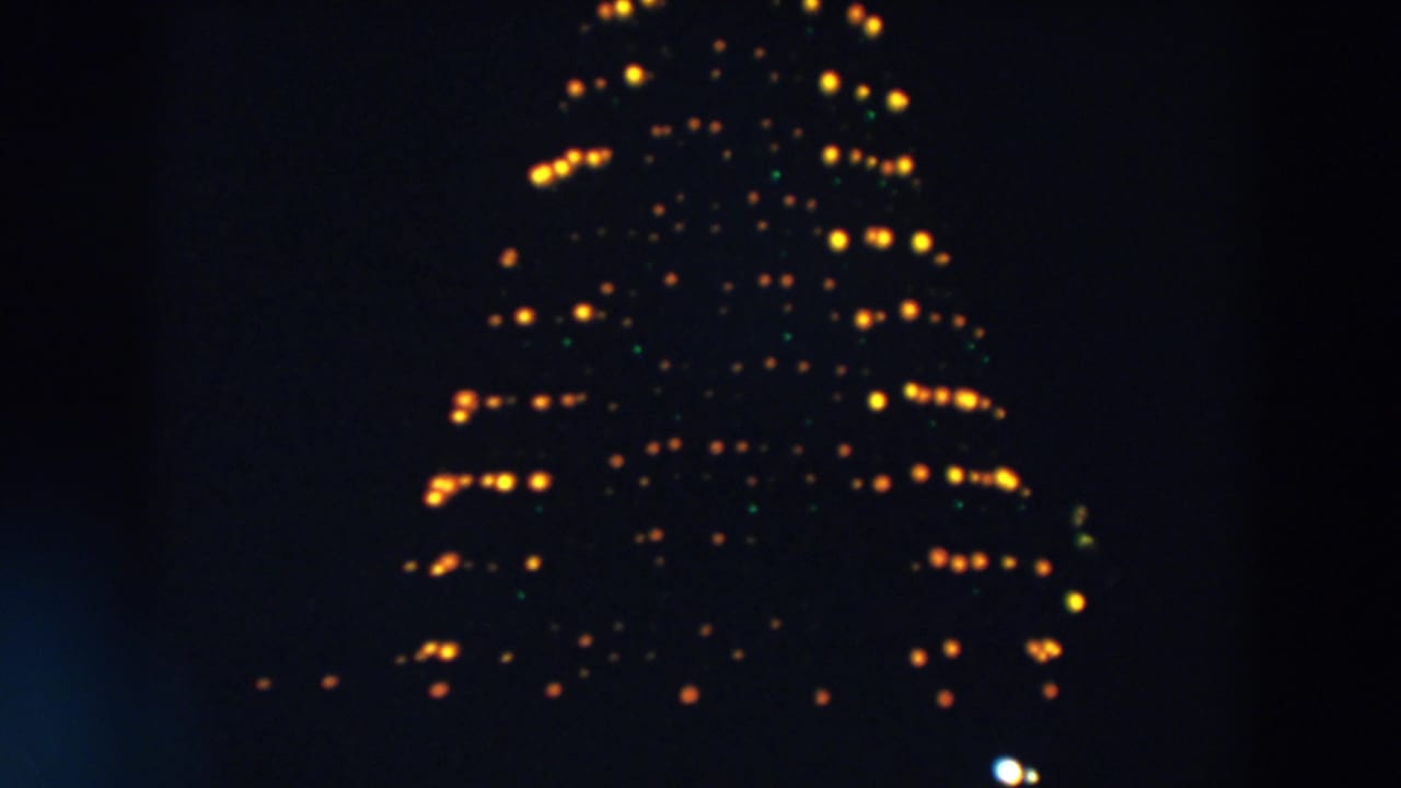 The 1957 Wheeling, Ohio frame shows a tall triangular light formation, with yellow bulbs and faint green points in soft focus.